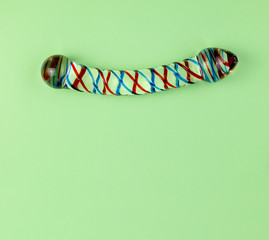 Beautiful evenly lit glass dildo on a plain green background with copy space.