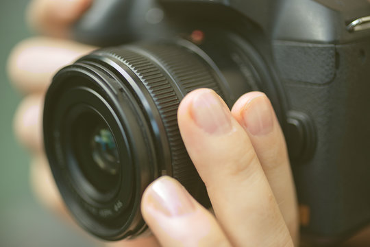Photographer hands holding a digital camera, focusing and taking photos, macro closeup
