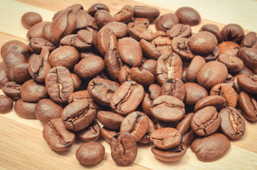 Heap of coffee grains on wooden board