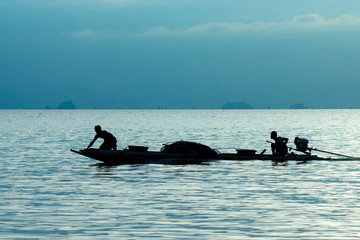 Naklejka premium Silhouette of minimal fishing boat in the blue hour on the lake.