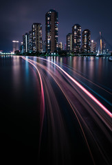 Night view of the luxury condominium in Tokyo next to the river with light trail from the boat....