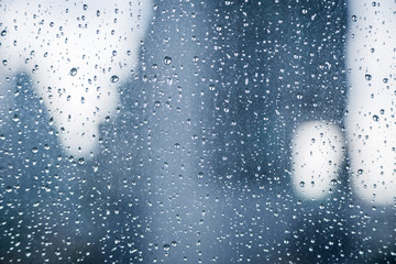 Abstract image of Rain drops on the dirty glass windows with modern office building