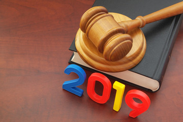 Numbers 2019 and wooden judge gavel on legal book as symbol of new laws of 2019