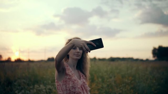 Beautiful Woman Enjoing Nature At Sunset.Girl Taking Photo And Smailing.Blonde Woman Taking Selfie At Sunset In Field.Selfie At Sunrise.Woman Portrait At Sunset.Female Takes Selfie At Amazing Sunrise.
