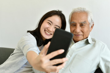 Asian family relationship, Daughter and elderly father using smartphone for selfie together, Senior...