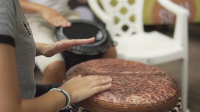 Female musician playing bongo drum during classes. Hands close up in slow motion