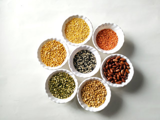 Uncooked pulses,grains and seeds in White bowls over white background. selective focus