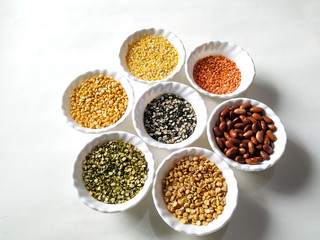 Uncooked pulses,grains and seeds in White bowls over white background. selective focus