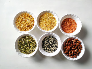 Uncooked pulses,grains and seeds in White bowls over white background. selective focus