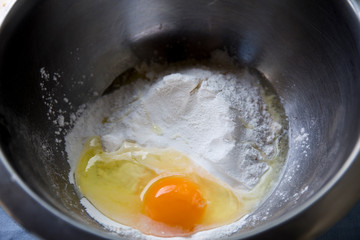 Broken egg and flour in a metal bowl
