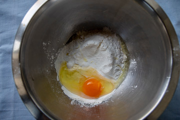 Broken egg and flour in a metal bowl