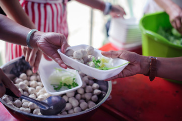 Poor people receiving food from donations : Homeless people are helped with food relief, famine relief : volunteers giving food to poor people in desperate need