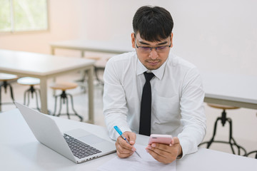 Fototapeta premium Young business man working at office with laptop, mobile and documents