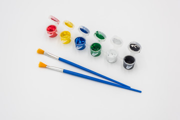 Colorful paints and brushes quietly placed on a white background