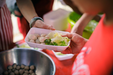 Hand offered to donate food from a rich man Share : Poor people receiving food from donations : Homeless people are helped with food relief, famine relief