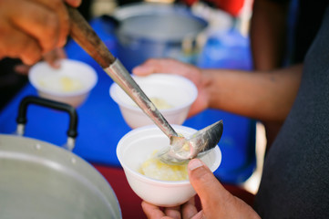 Hand offered to donate food from a rich man Share : The concept of social sharing : Poor people receiving food from donations : Homeless people are helped with food relief, famine relief