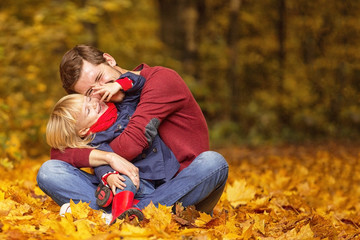 Father and daughter hug and laugh in the autumn park.