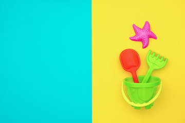 Multicolored set children's toys for summer games in sandbox or on sandy beach on blue yellow background with copy space. Top view Flat lay Concept. Template for your text or design