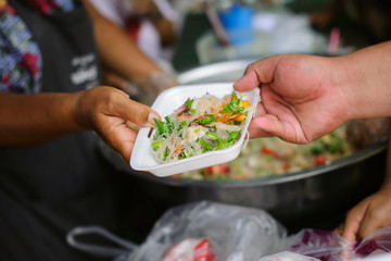 The concept of humanitarianism : The hands of refugees have been aided by charity food to alleviate hunger : Feeding Concepts : Hand offered to donate food from a rich man Share