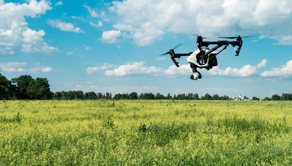 Drone in flight over the field. The operator of the drone. Forest, sky and clouds.