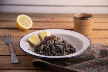 Plate of black rice with squid and prawns or Valencian black paella