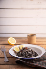 Plate of black rice with squid and prawns or Valencian black paella