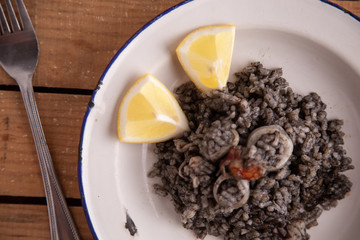 Plate of black rice with squid and prawns or Valencian black paella
