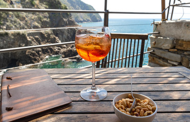 Aperol spritz cocktail close up on a wooden table in a restaurant. Riomaggiore in Cinque Terre, Italy