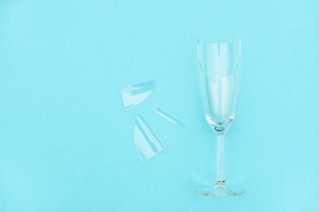 Broken champagne glass with splinters on blue background with copy space. Concept fight against alcoholism, drunkenness and refusal of alcohol. Creative Top view Flat lay