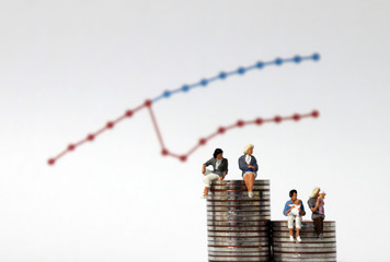 Miniature women sitting on a pile of coins of different heights. The concept of women's childbirth...