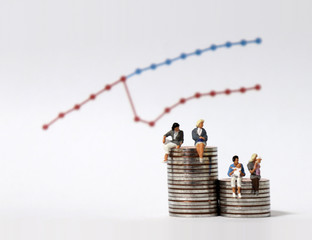 Miniature women sitting on a pile of coins of different heights. Miniature people and graph.