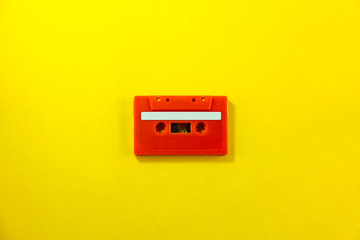 Top view of red classic tape cassette against yellow isolated background.