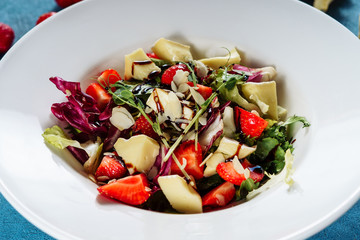 Salad with Brie Cheese and Strawberry Closeup. Vitamin Natural Tasty Appetizer Dish Camembert, Red Ripe Berry and Lettuce Green Leaves Seasoned with Balsamic Vinegar in White Plate