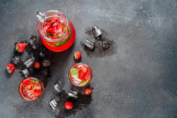 Glasses and Carafe with Bio Strawberry Beverage. Cold Refreshing Mixed Ripe Berries and Mint Ingredient in Vitamin Drink. Splash of Water and Ice. Summer Sweet Tasty Punch Cocktail Flat Lay