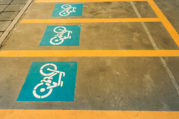 A white painting of a bicycle on the asphalt of the road that means mark of bicycle parking area.