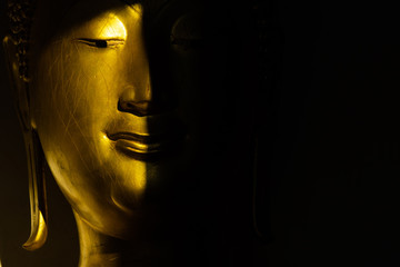 close up mouth and face golden buddha statue in the light and shadow of sun at Wat Pra Sri Mahathat...