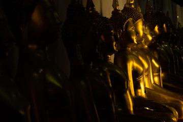 Naklejka premium close up row of golden buddha statue in the light and shadow of sun at Wat Pra Sri Mahathat temple, Phitsanulok province, Thailand