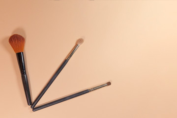 Three brushes are laying on a pink surface