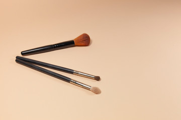 Three brushes are laying on a pink surface