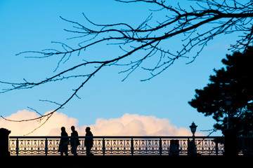 silhouette people and dried tree branch on bridge against blue sky and drama colour of clouds at Kanazawa Castle, Japan
