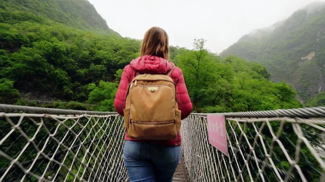 Young Caucasian Female Traveler Walking Through Suspension Bridge at Taroko Gorge National Park in Taiwan. Active Solo Travel