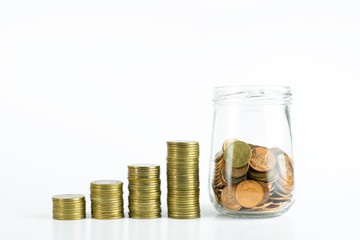 stack of golden coins and a glass jar of bronze coins on isolated white background.
