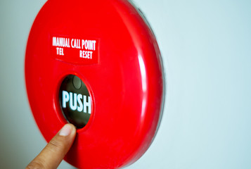 finger is pushing a fire alarm button equipment  on the wall
