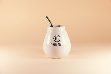 A cup of yerba mate tea is sitting on a pink surface