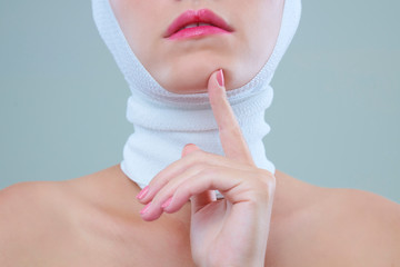 Young woman with bandage over her head and neck touching her chin