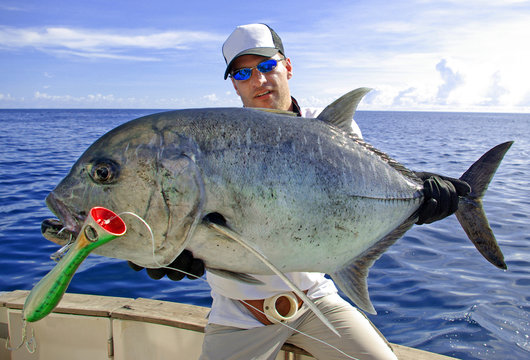 Deep sea fishing, catch of fish, big game fishing, boat fishing, lure fishing, sea fishing. Fisherman holding a big Trevally jack.