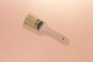 A brown paintbrush is laying on a pink surface
