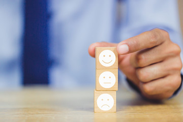 customer pressing smiley face emoticon on wood cube, Service rating, satisfaction concept.