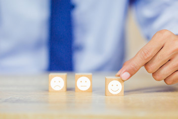 customer pressing smiley face emoticon on wood cube, Service rating, satisfaction concept.