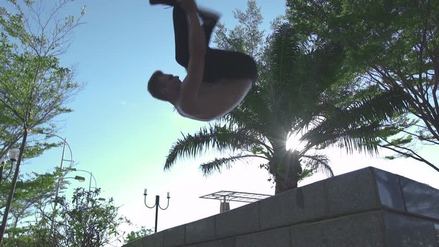 Sportsman training parkour jump in summer park. Athlete man doing freerunning jump in city park. Active youth lifestyle. Adrenaline sport training. Parkour sport. Workout outdoor.